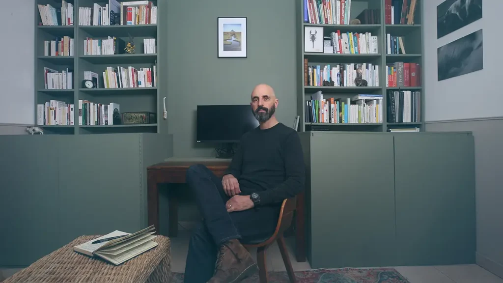Alexis Courraud, hypnothérapeute, assis dans son cabinet à Parçay-sur-Vienne entouré de livres — accompagnement en reconstruction post-traumatique en Touraine