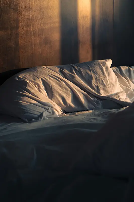 Lit défait dans la pénombre — insomnie post-traumatique et hypervigilance nocturne, hypnose Azay-le-Rideau Touraine