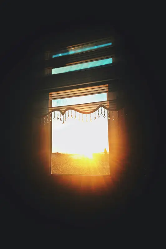 Lumière dorée du matin filtrant par une fenêtre dans une pièce sombre — renaissance et reconstruction identitaire après une rupture amoureuse, hypnose Loches Touraine