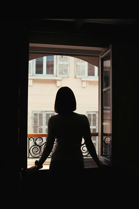 Silhouette d'une femme devant une fenêtre ouverte — isolement et comportement d'évitement liés au TSPT et aux phobies post-traumatiques, hypnose Chinon Azay-le-Rideau