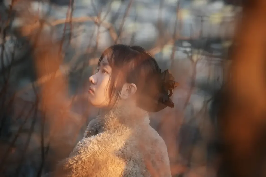 Femme de profil regard vers le ciel à travers des branches — dissociation et mémoire somatique après une agression sexuelle