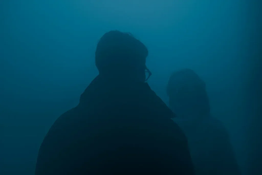 Deux silhouettes dans un brouillard bleu dense — hypervigilance et mémoire traumatique corporelle après la guerre