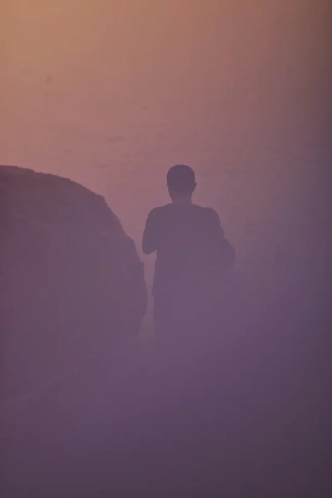 Silhouette coincée entre deux rochers dans le brouillard violet — retour impossible en vie civile après la guerre