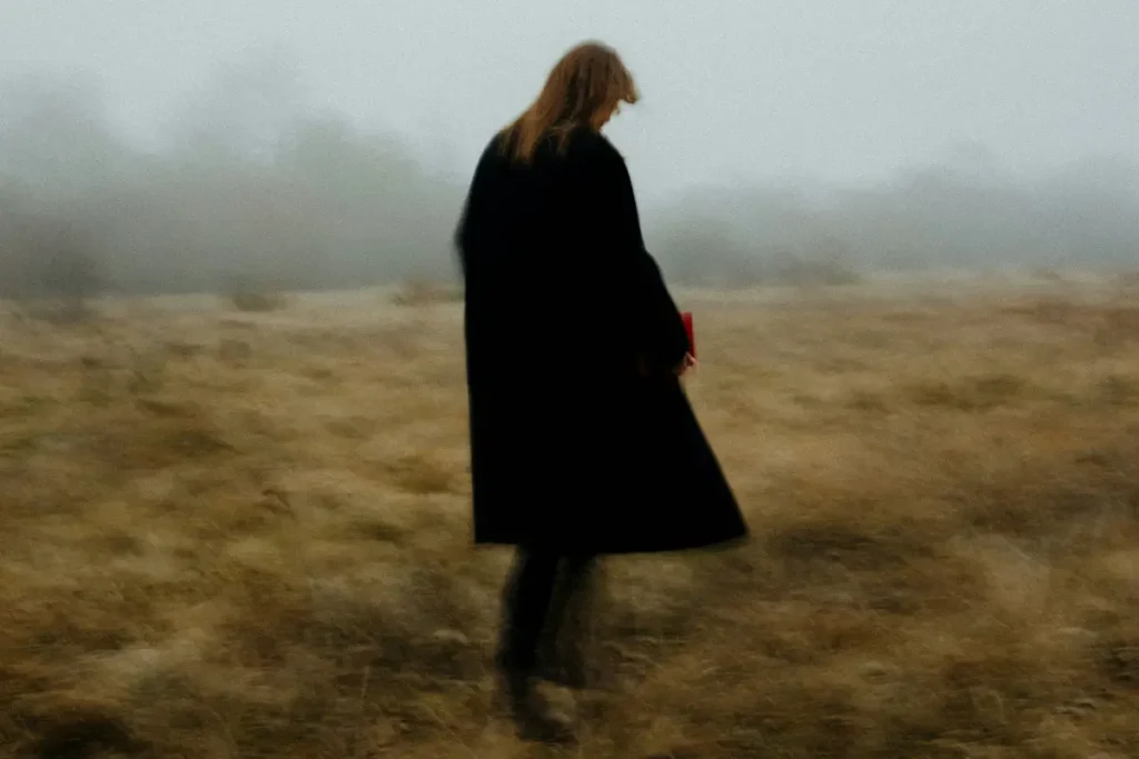 Figure floue marchant dans un champ brumeux, illustrant l'évitement post-traumatique