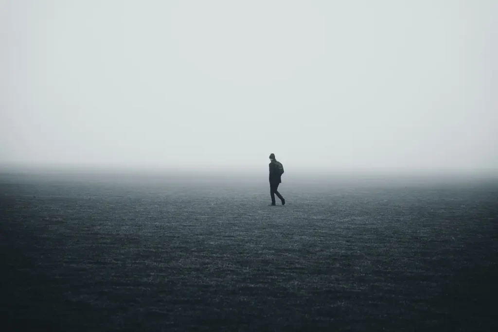 Silhouette solitaire marchant dans un champ brumeux et vide, illustrant l'inquiétude chronique après un trauma
