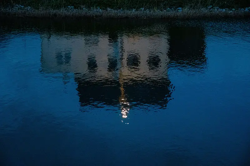 Reflet d'un bâtiment dans l'eau la nuit, évoquant ce que l'hypnose et les émotions révèlent de l'inconscient