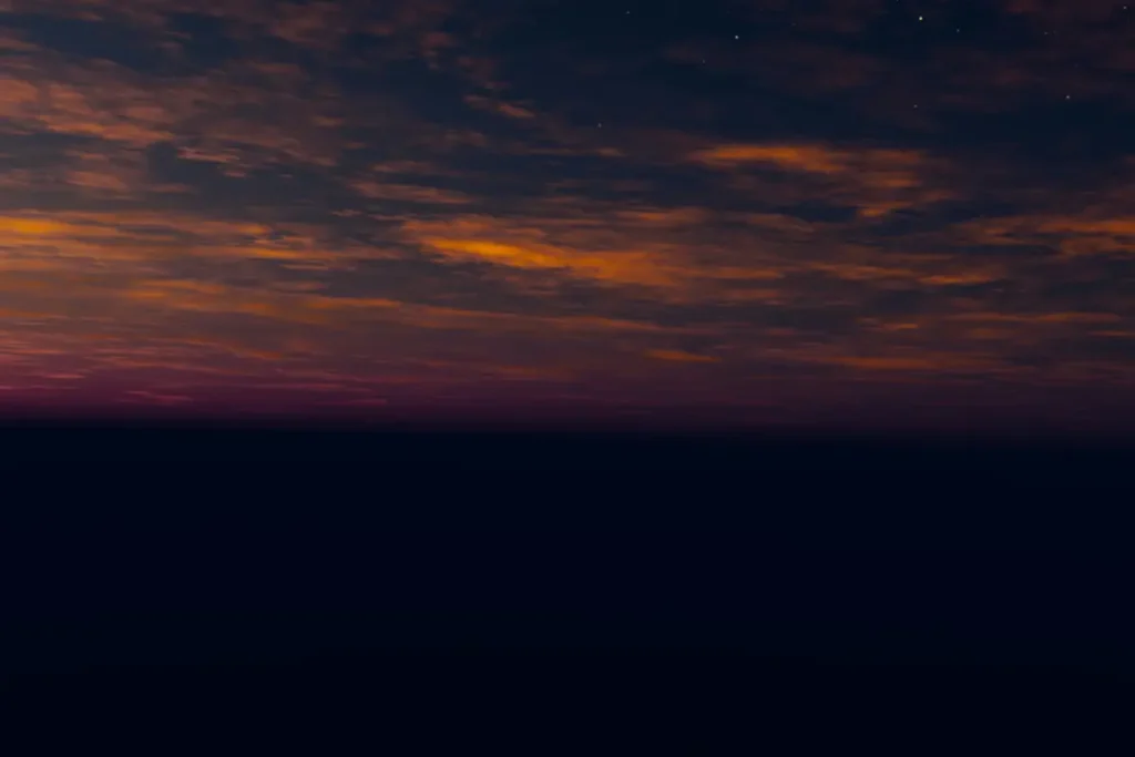 Ciel nocturne étoilé avec fine bande orange à l'horizon, hypnose spécialisée pour le conjoint accompagnant isolé en expatriation