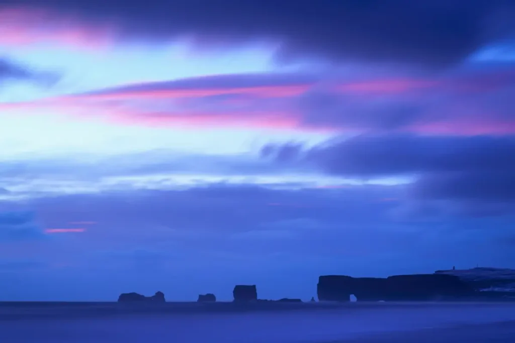 Horizon bleu au crépuscule avec silhouettes rocheuses lointaines, hypnose spécialisée pour le trauma vicariant des humanitaires expatriés